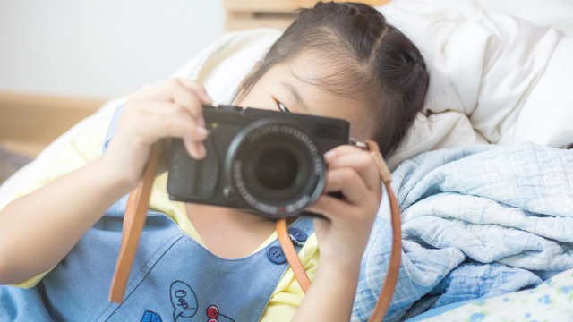 Little girl enjoying take photo with camera in room