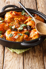 African cuisine chicken stew with eggplant, almonds in tomato sauce close-up in a pan. vertical