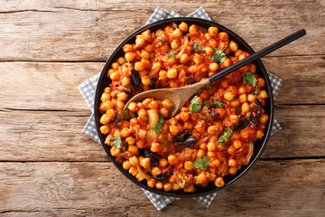 Spicy Middle Eastern chickpea food with eggplant, tomatoes, onions, herbs and spices closeup on a plate. Horizontal top view