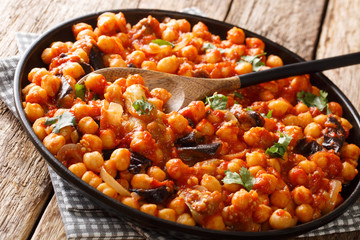 Spicy Middle Eastern chickpea food with eggplant, tomatoes, onions, herbs and spices closeup on a plate. horizontal