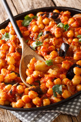 Israeli vegetarian cuisine stew of chickpeas with eggplant, tomatoes, onions and spices closeup on a plate. vertical