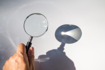 Left hand holding old magnifying glass on white background, Light and Shadow