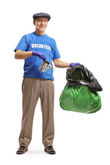 Elderly male volunteer putting a tin can in a plastic garbage bag