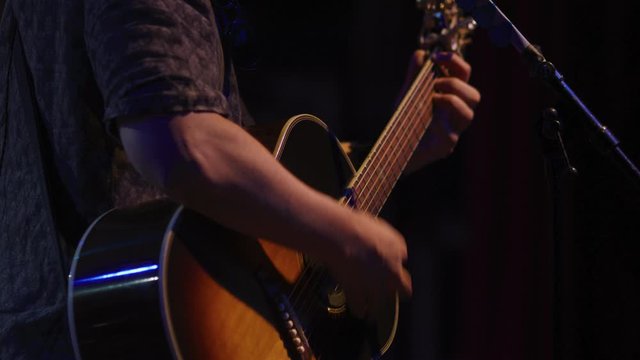 Slow motion of musician playing acoustic guitar on stage