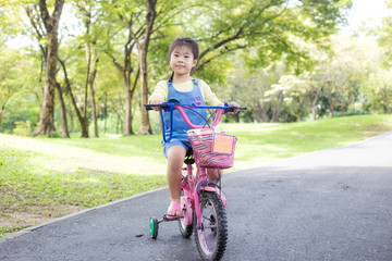Adorable little girl enjoying with bike in public city park