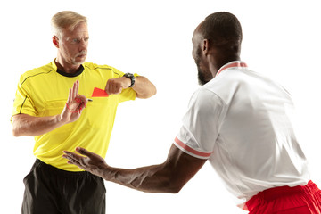 Referee showing a red card to a displeased african-american football or soccer player while gaming...