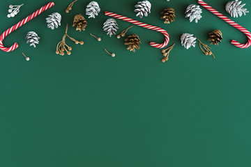 Christmas background. Flat lay and top view of fir tree cones, wreaths, red decorations and white balls on green background. Christmas, winter and new year concept with copy space