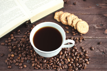 Cup of coffee, coffee beans and cookies on a dark wooden table
