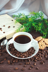 Cup of coffee, coffee beans and cookies on a dark wooden table