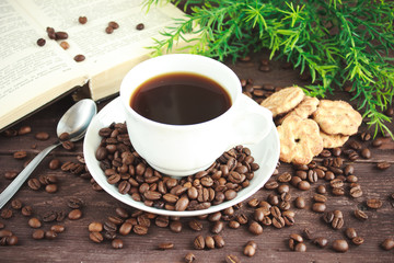 Cup of coffee, coffee beans and cookies on a dark wooden table