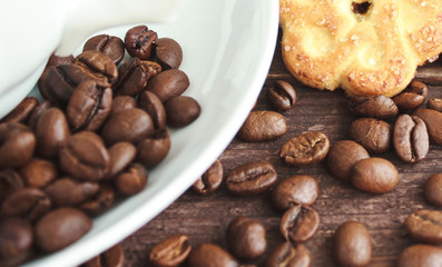 Cup of coffee, coffee beans and cookies on a dark wooden table