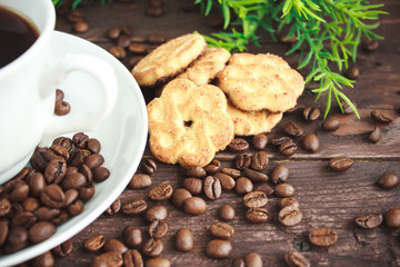 Cup of coffee, coffee beans and cookies on a dark wooden table