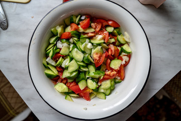 Tomatoes, fresh cucumbers and onion salad. The salad in a plate on the table. Chopped and mixed vegetables. Eco friendly products. Top view