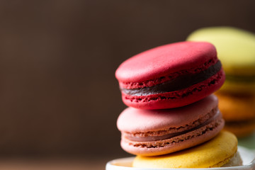 Pile of sweet and colourful french macaroons on wood background.