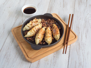 Fried dumplings Gyoza in a frying pan, soy sauce, and chopsticks on a white wooden background, top view. 