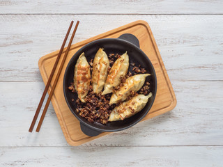 Fried dumplings Gyoza in a frying pan, soy sauce, and chopsticks on a white wooden background, top...