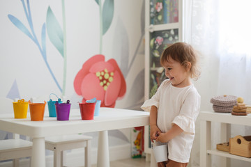 toddler sorts colorful toys by colored buckets