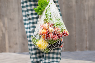 Woman walking and shopping fruits and vegetables with reusable cotton Eco produce bag. Zero waste lifestyle concept
