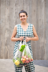 Woman walking and shopping fruits and vegetables with reusable cotton Eco produce bag. Zero waste lifestyle concept