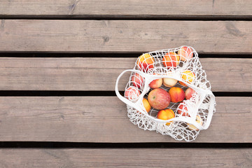 Female hand with cotton eco bag on wooden grey background. Zero waste concept