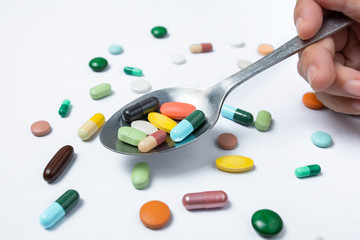 Colorful capsules and pills on spoon. Concept of health
