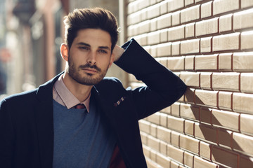 Attractive man wearing british elegant suit in the street. Modern hairstyle.