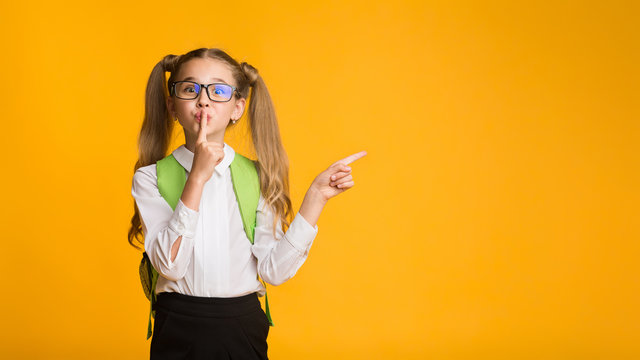Elementary Student Putting Finger To Lips Pointing Aside, Yellow Background