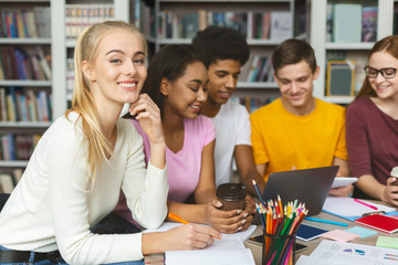Fototapeta premium Cheerful college students studying together in library