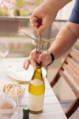 Man opening bottle of wine on the terrace