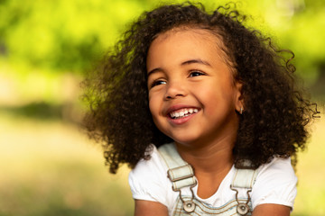 Cute afro girl smiling broadly outdoors, having picnic with parents