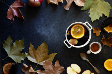White mug with mulled wine. Autumn and winter warm alcoholic drink. Autumn leaves, honey, apples, oranges, vintage dishes. Autumn cozy mood. Flat lay, dark background.