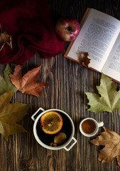 Warm autumn and winter alcoholic drink mulled wine. Honey, autumn leaves, apples, a book and a woolen sweater on a wooden background. Autumn cozy mood. Autumn background. Flat lay. Vertical