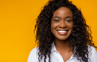 Portrait of smiling afro woman on yellow background