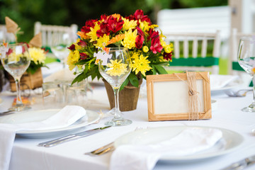 Garden wedding table set up decoration - fresh red and yellow flowers and a blank photo frame/board