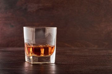 A full glass of whisky with ice on a wooden table