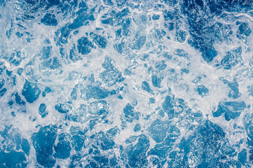 Pale blue sea surface with waves and foam, abstract background