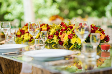 Wedding table set up decoration made of red and yellow fresh flowers. Rustic/ garden wedding decoration