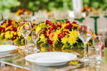 Wedding table set up decoration made of red and yellow fresh flowers. Rustic/ garden wedding decoration