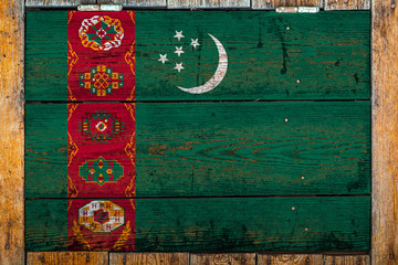 National flag of Turkmenistan on a wooden wall background.The concept of national pride and symbol of the country.Flag painted on a wooden fence with metal nails.