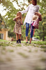 Fototapeta premium Mother and school girl going home from school.