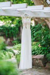 Wedding dress hanging outdoor on a wooden construction