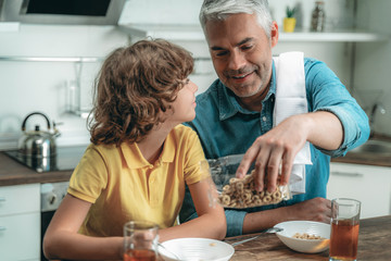 Happy son with father heaving breakfast at kitchen