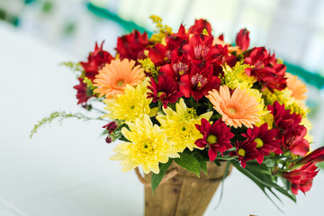 Wedding table decoration made of red and yellow fresh flowers.