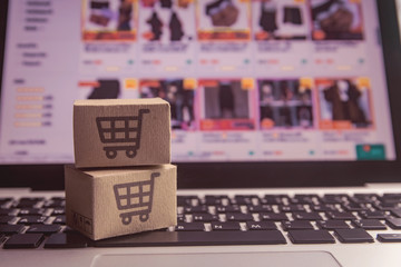 Online shopping - Paper cartons or parcel with a shopping cart logo on a laptop keyboard. Shopping service on The online web and offers home delivery.