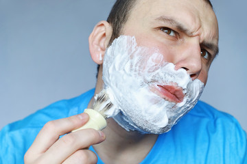 A man shaves in front a mirror. Shaving foam. Disposable razor.