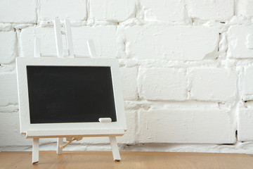 Close-up of a miniature chalk board with chalk stains and chalk on a white brick wall background, selective focus