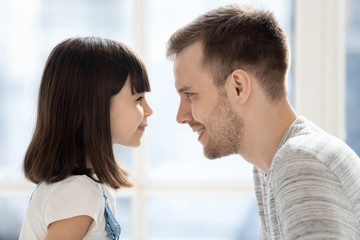 Fototapeta premium Cute little child daughter make funny face looking at dad