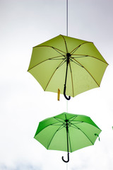 Wales, the historic town of Caernarfon.. Above one of the old medieval streets whimsical green umbrellas are strung at roof height. A touch of humour in an historic town.