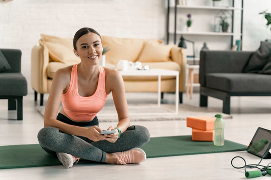 Jolly sporty girl relaxing with gadgets indoors stock photo