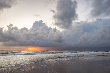 Threating storm clouds over sea while the sun is setting on the horizon
